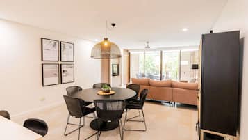 A modern dining area with a round table, black chairs, and a hanging light fixture.