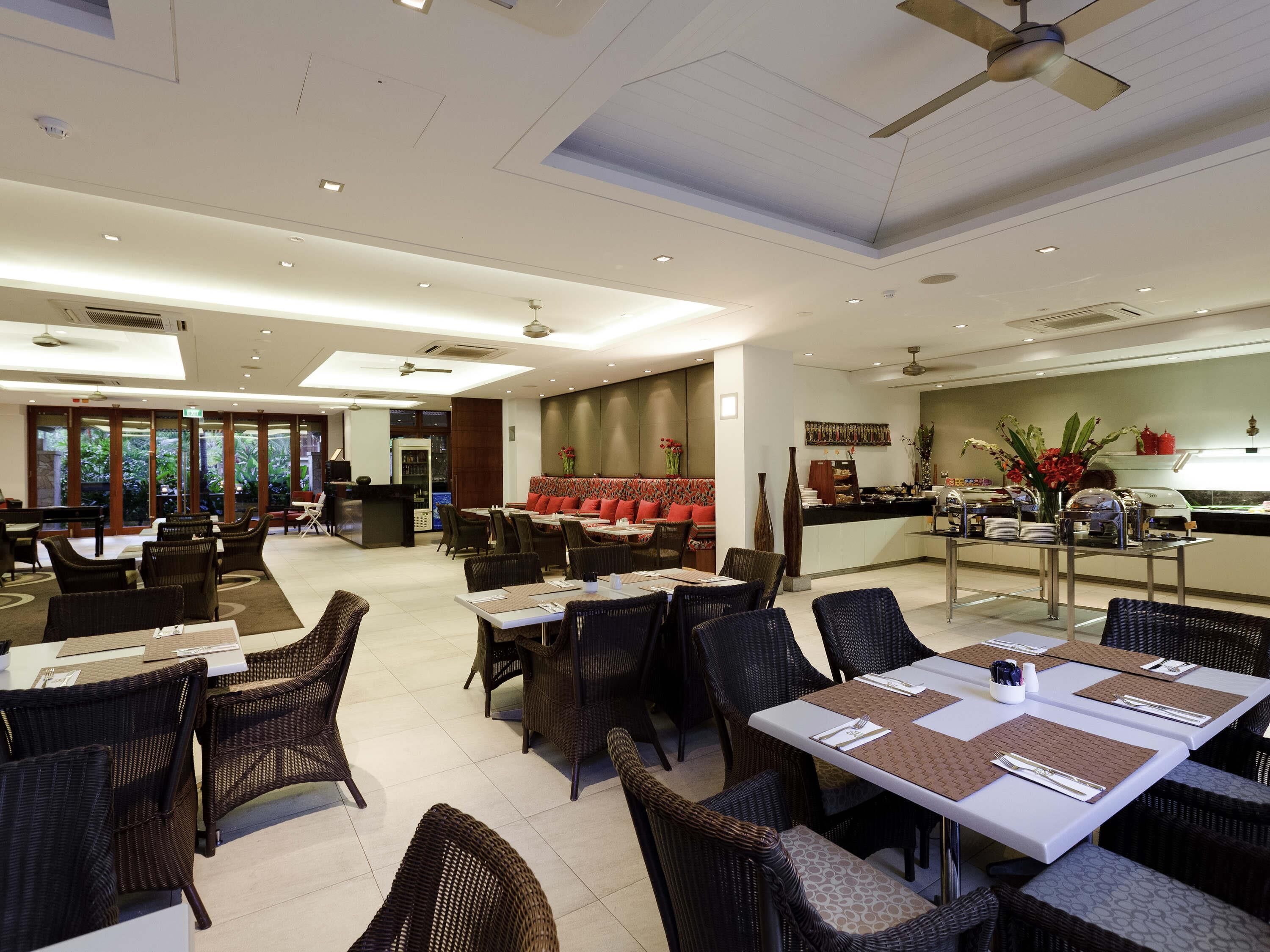A spacious restaurant with high ceilings, modern lighting, and a variety of seating options including tables and chairs.