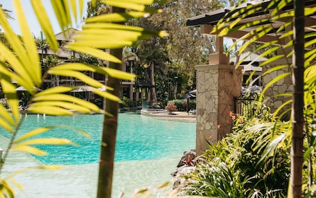 A clear pool surrounded by lush greenery and stone structures.