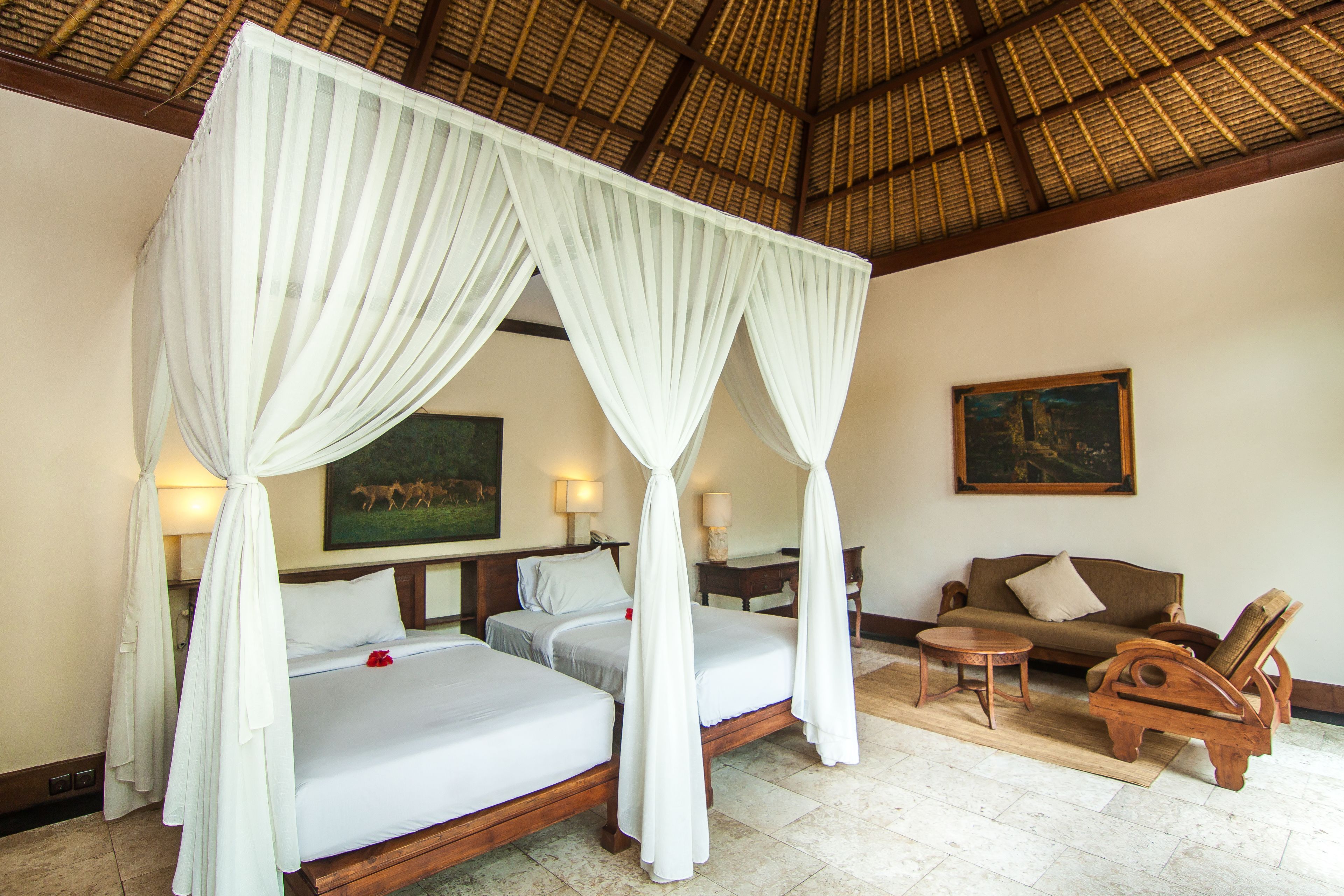 A room with a four-poster bed, a sofa, a chair, and a small table.