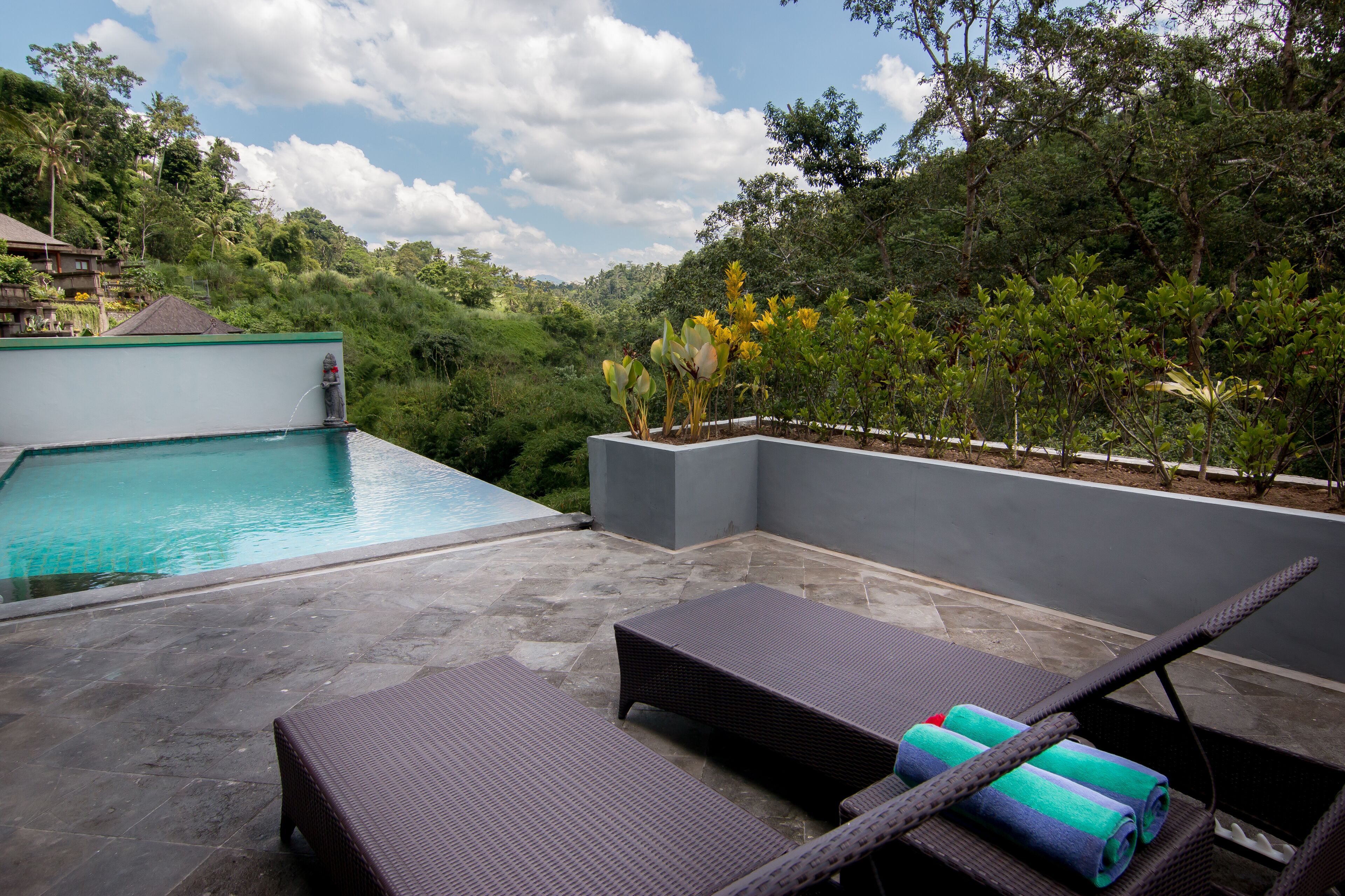 A rooftop pool area with lounge chairs and a view of lush greenery.