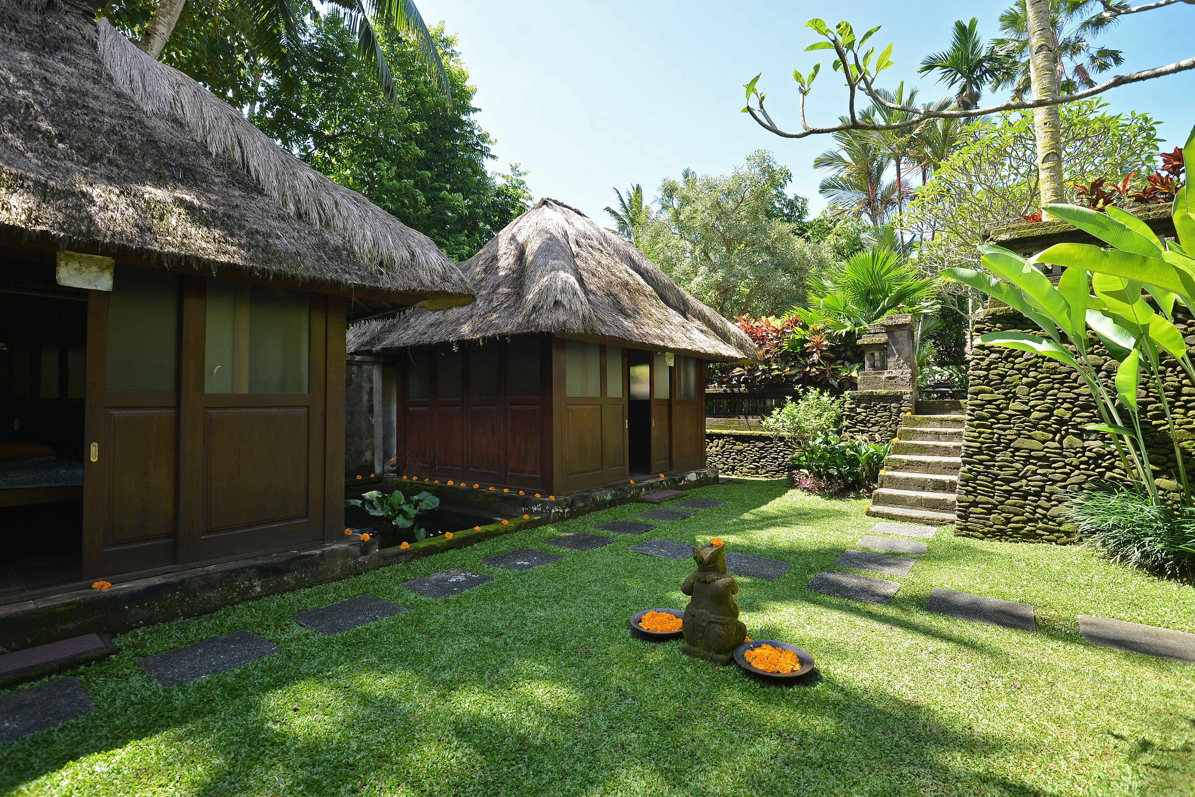 A thatched-roof bungalow with a stone pathway leading to a wooden door.