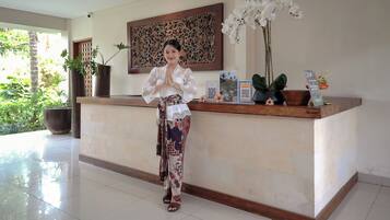 A reception area with a wooden counter, potted plants, and a decorative wall piece.