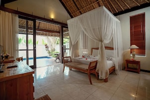 A spacious bedroom with a wooden bed, a wooden desk, and a large window.