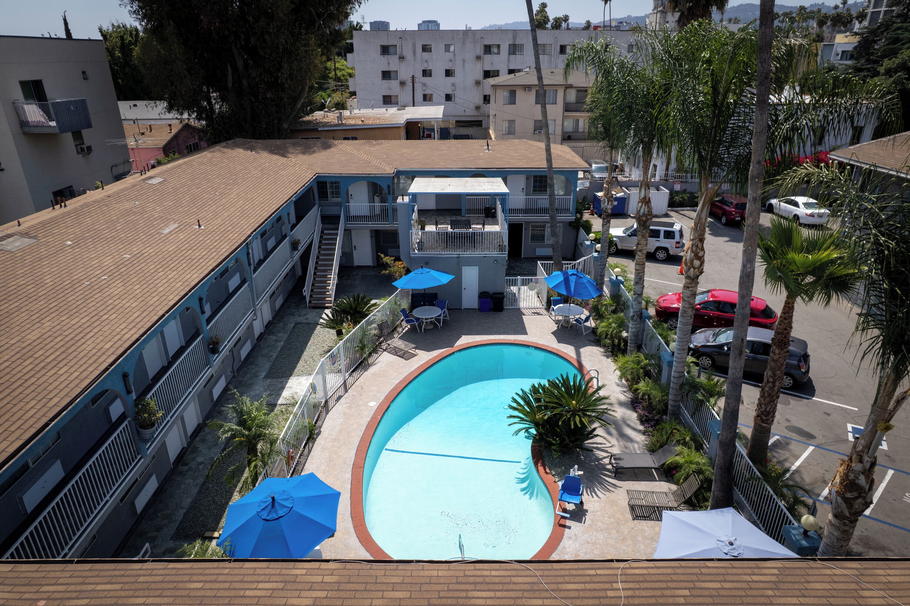 A multi-story building with a rooftop pool, outdoor seating, and palm trees.