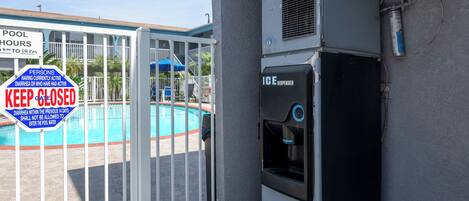 A pool area with a sign indicating pool hours and a 'KEEP CLOSED' notice due to health concerns.