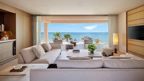 A spacious living room with a large sofa, a coffee table, and a TV. There is a view of the ocean through large windows. - Sani Asterias (Kassandra)