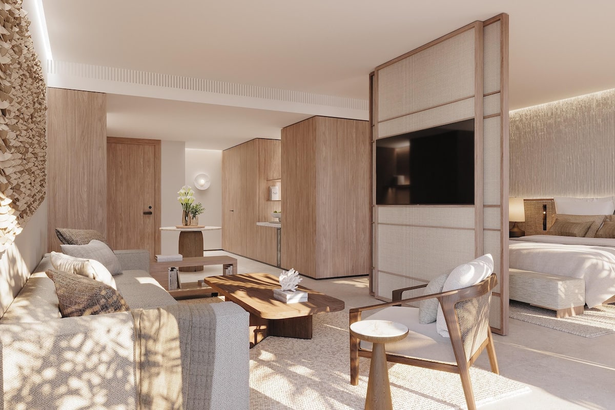 A modern hotel room with a large bed, a TV, a sofa, and a coffee table.