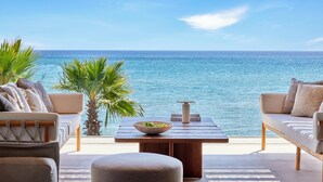 A seaside patio with a sofa, a table with a bowl, and a view of the ocean.