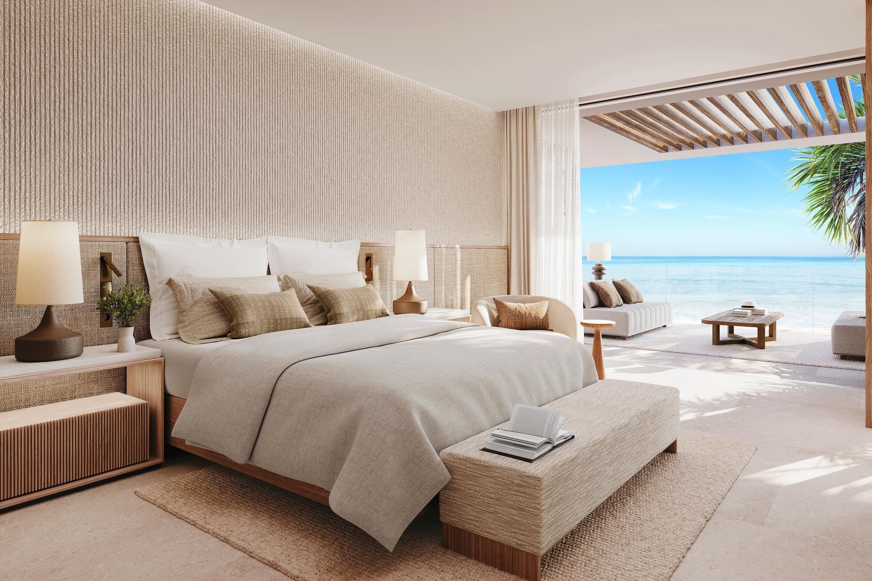 A modern bedroom with a large bed, bedside tables, a reading bench, and a view of the ocean.