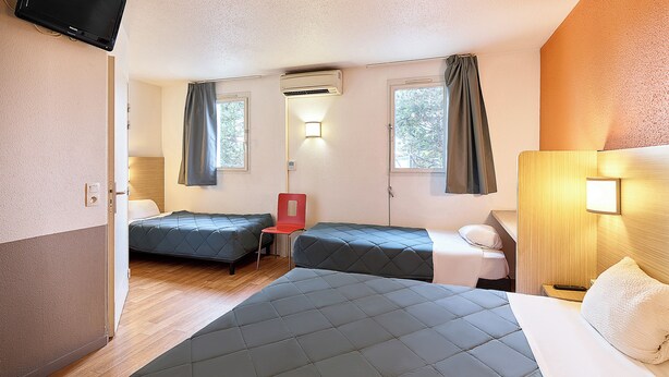 A hotel room with two beds, a chair, a desk with a lamp, and an air conditioning unit. - Première Classe Paris Est - Rosny sous Bois (Rosny-sous-Bois)