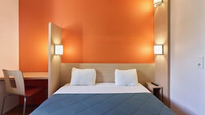 A hotel room with a bed, two bedside lamps, a desk, and a chair.