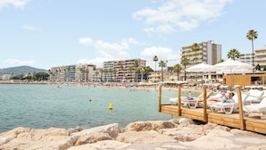 A beachside hotel with a wooden deck, lounge chairs, and umbrellas.