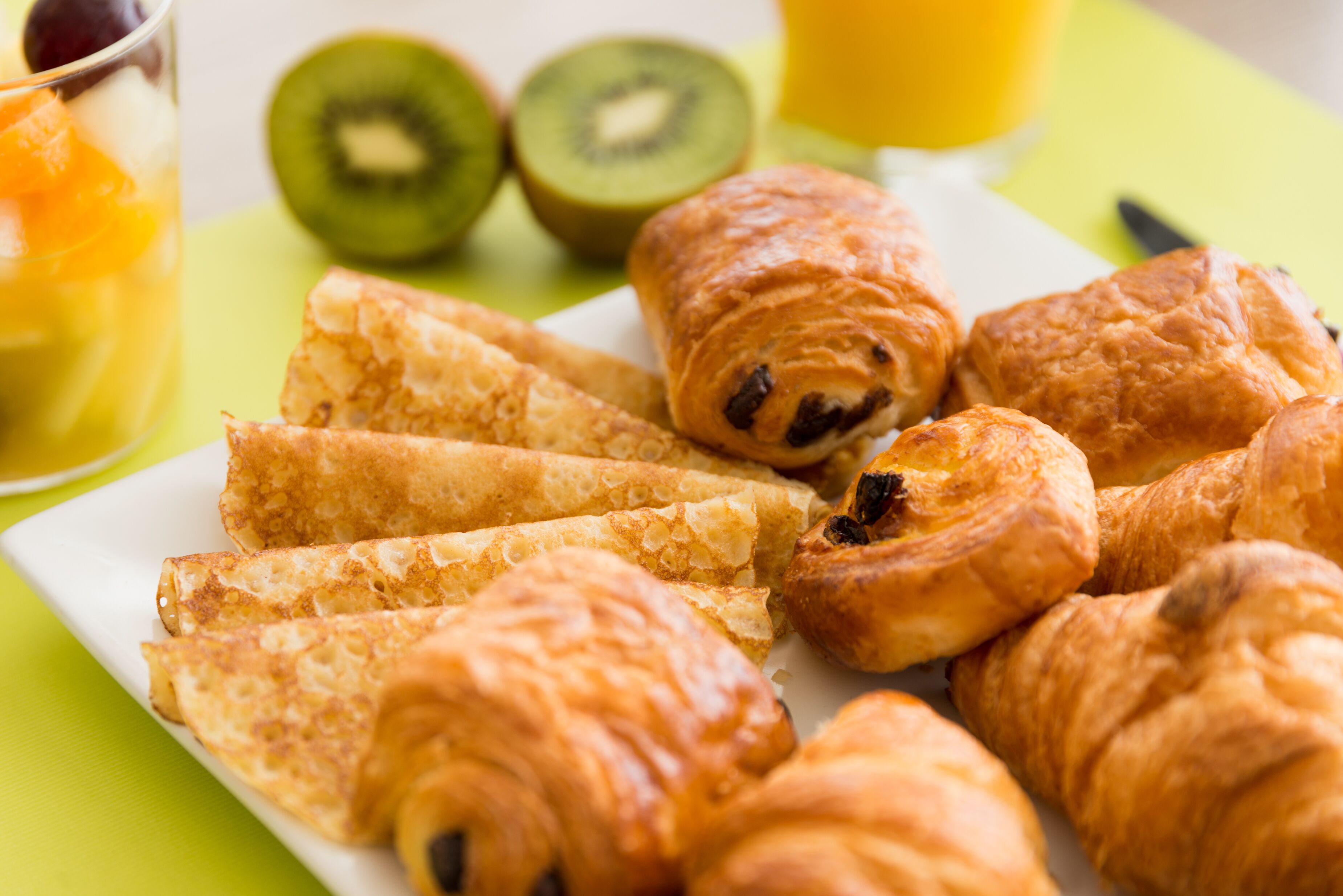 Un plato de cruasanes y frutas cortadas sobre una mesa.