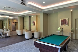 Ein Billardtisch in der Hotelhalle mit Sitzgelegenheiten und einem Spiegel.