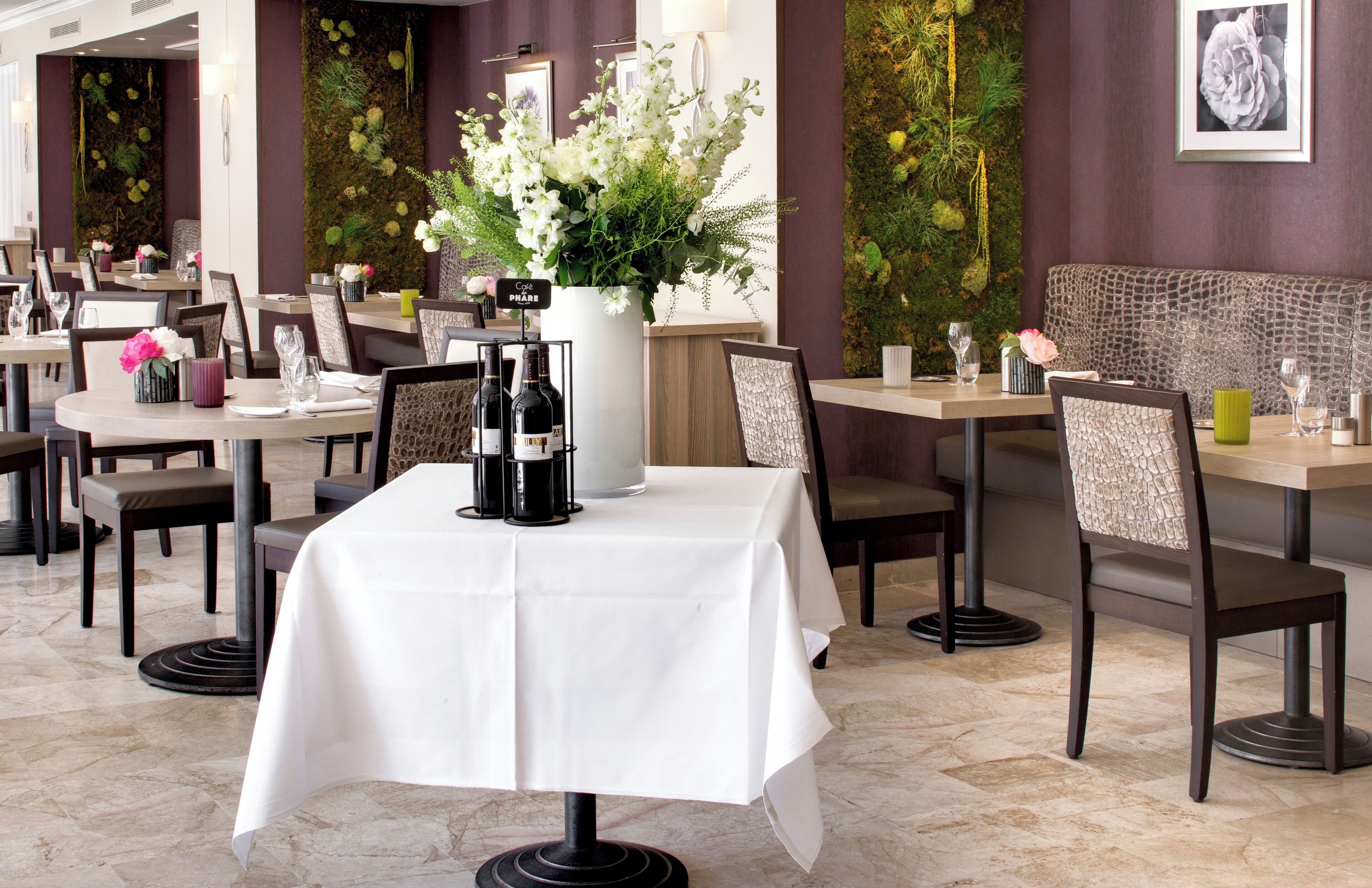 Interior de restaurante con mesas dispuestas para comer, un jarrón de flores y un letrero que indica una cafetería.