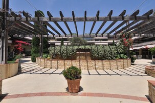 Un espace extérieur abrité, doté d’une pergola, de jardinières en pierre et d’une fontaine centrale.