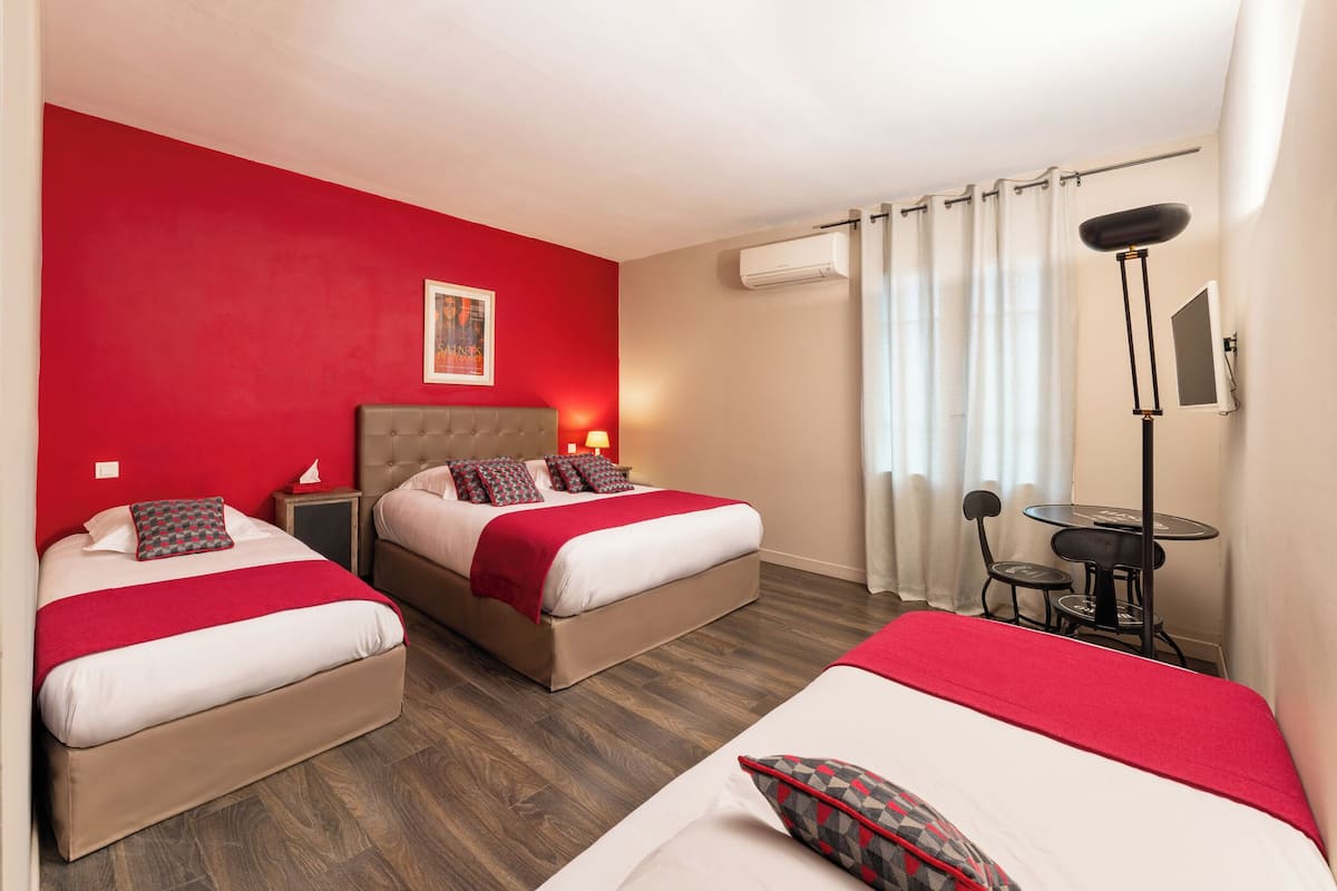A hotel room with two beds, a desk, and a chair.