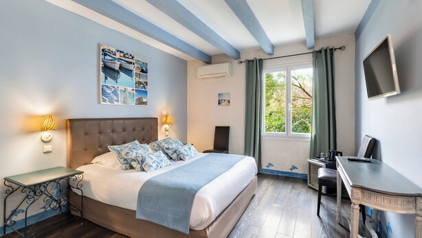 A bedroom with a bed, bedside tables, a desk, and a window with curtains. - Hôtel ERMITAGE (Les Angles)