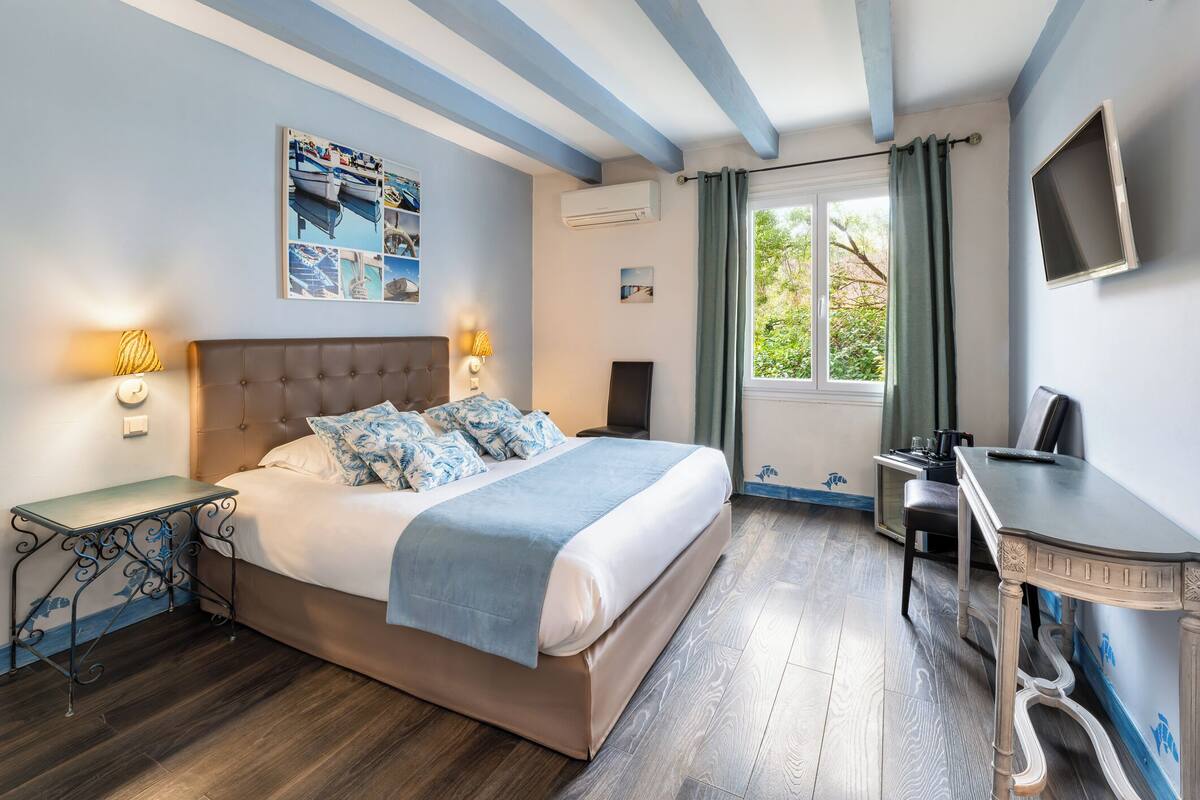 A bedroom with a bed, bedside tables, a desk, and a window with curtains.