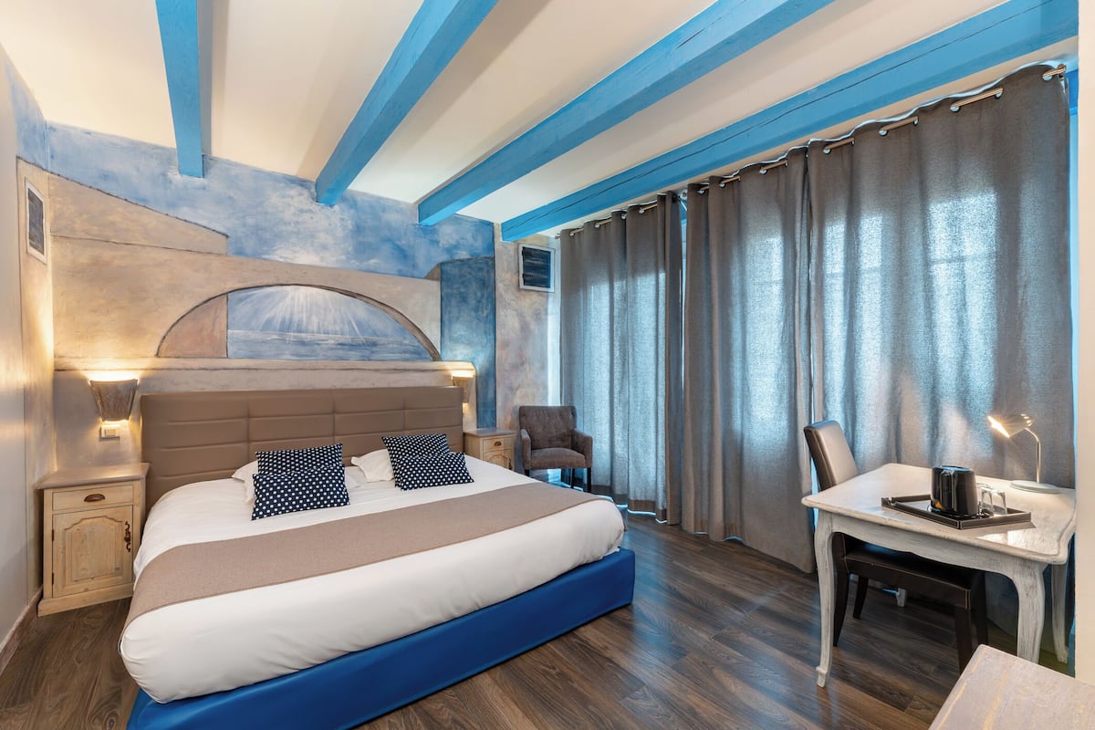 A modern hotel room with a large bed, a desk, and a chair.