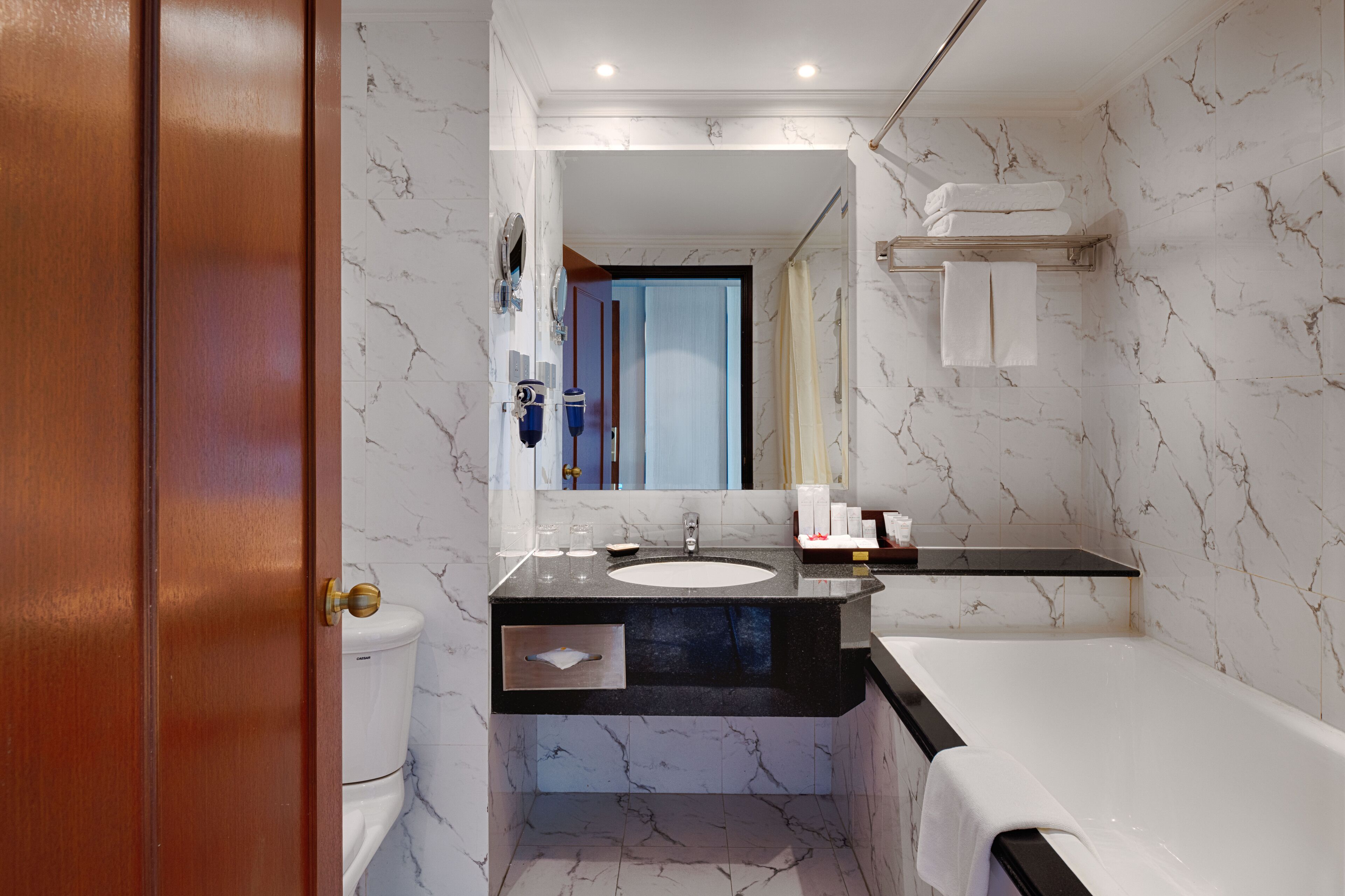A modern bathroom with a marble sink, a bathtub, and a toilet.
