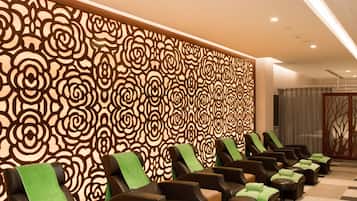 Un área de spa con varias sillas de masaje, un muro con diseño y un suelo a cuadros.