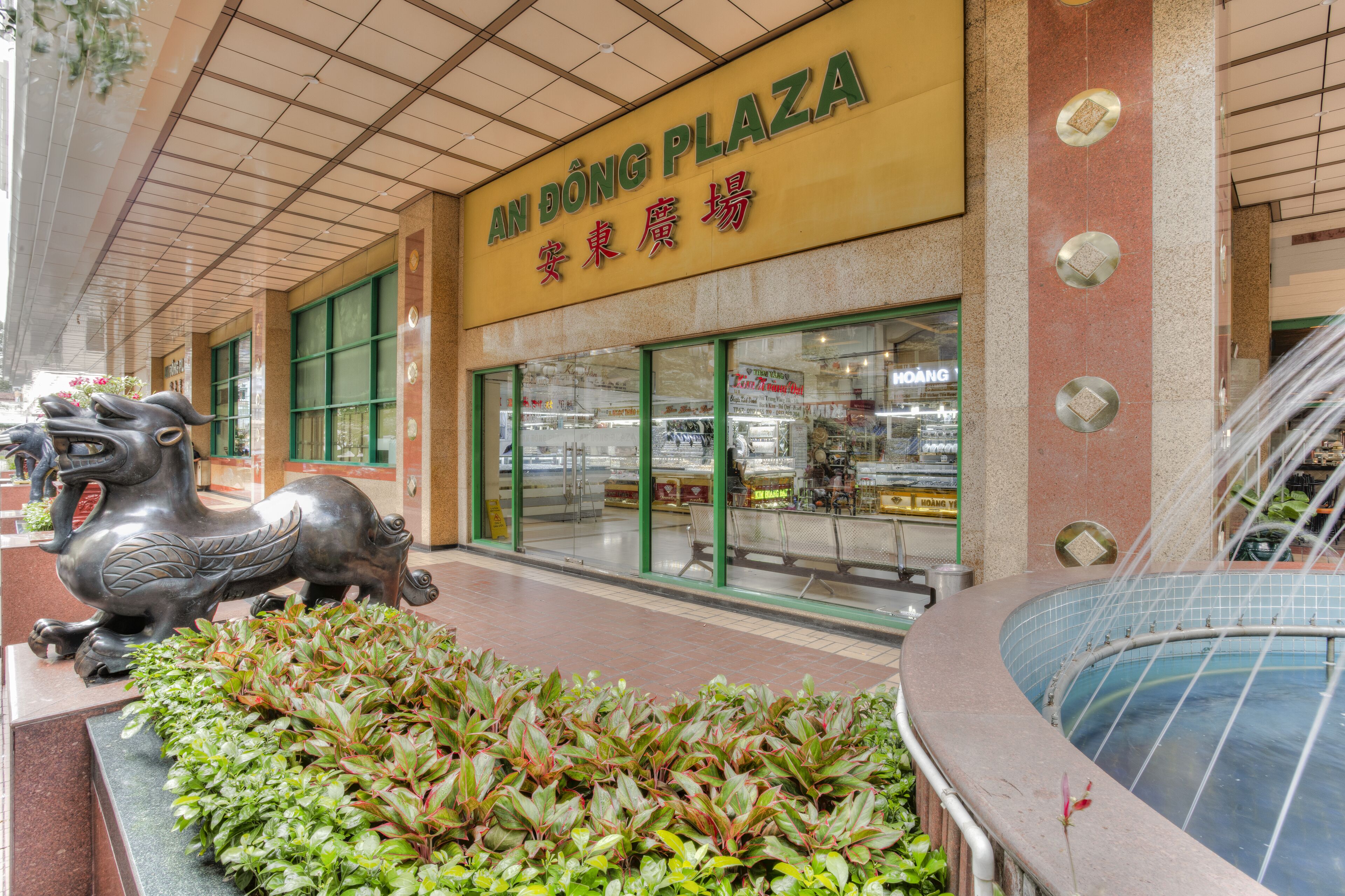 A shopping plaza with a statue of a mythical creature, a fountain, and a pool.