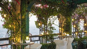 Ein Restaurant mit Außenbereich, Tischen und Stühlen sowie hängenden Pflanzen.