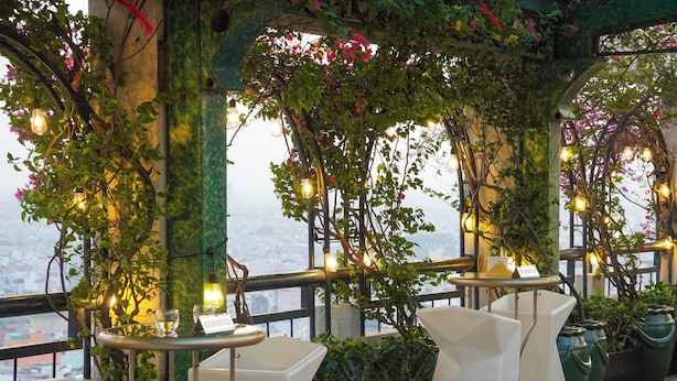 A restaurant with outdoor seating, tables with chairs, and hanging plants. - Windsor Plaza Hotel (Ho Chi Minh City)