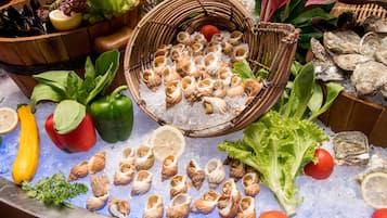 A variety of fresh seafood and vegetables displayed on ice, including mussels, oysters, and bell peppers.