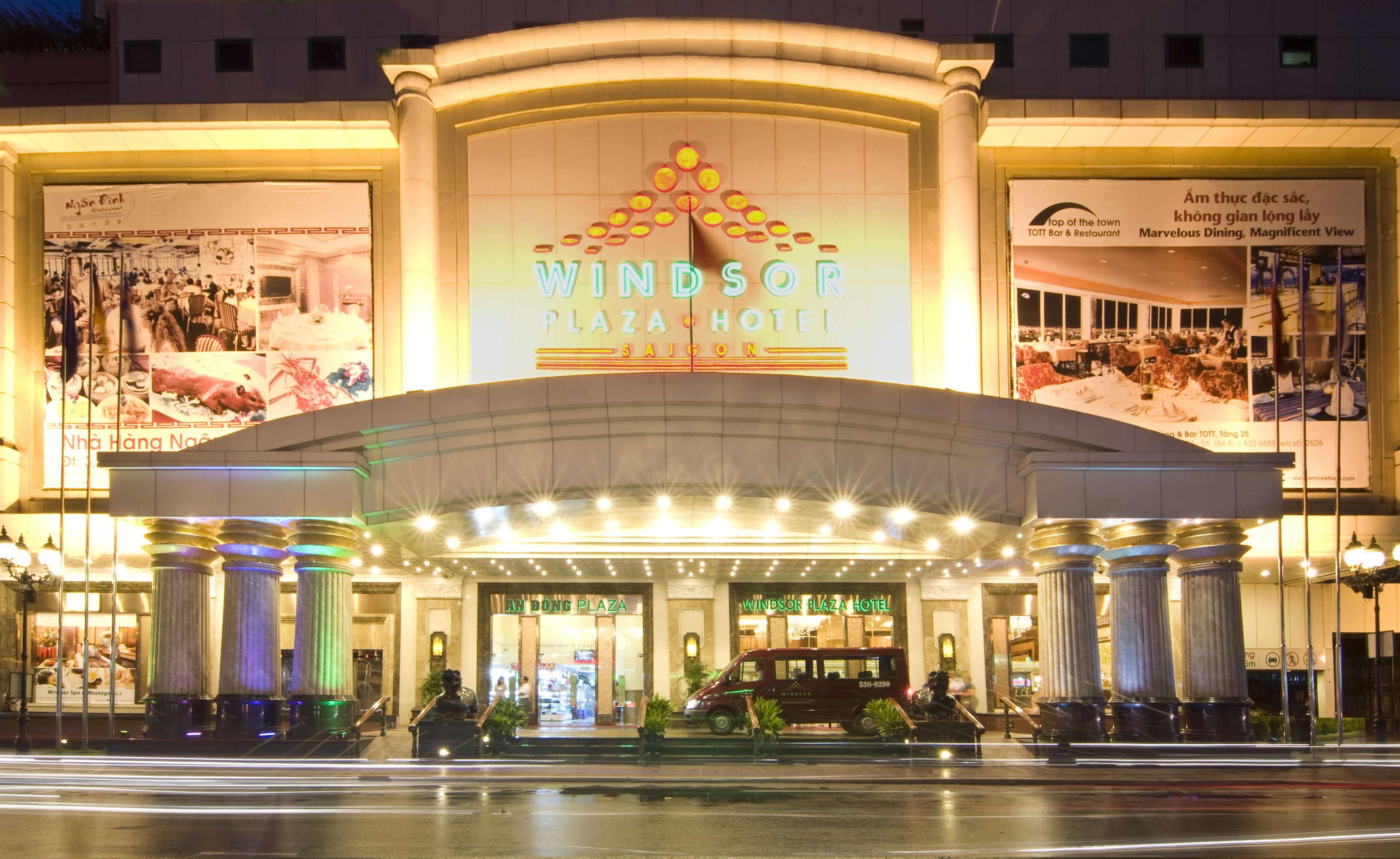 The Windsor Plaza Hotel entrance with a large illuminated sign, columns, and a view of the interior through the glass doors.