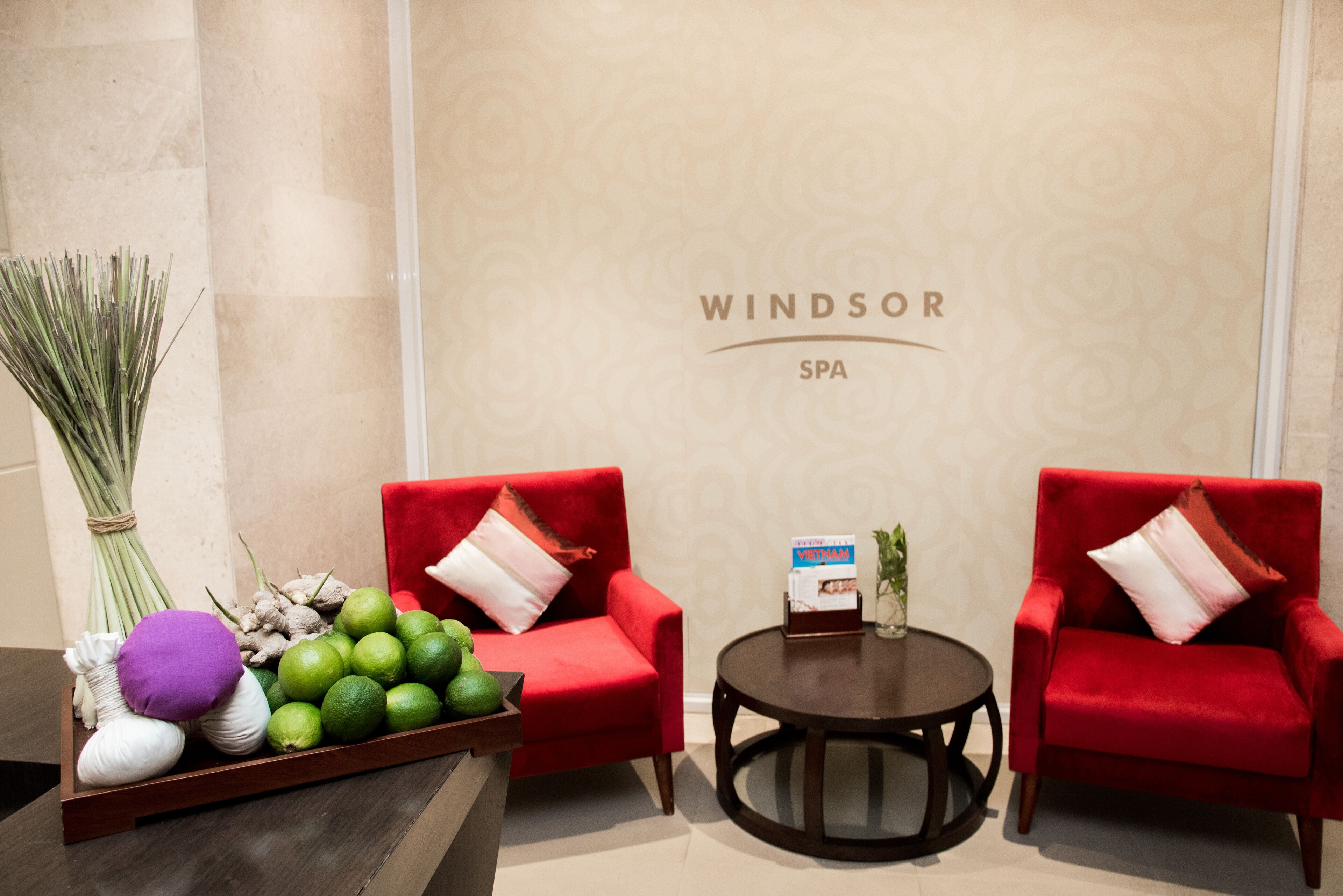 A reception area with two red armchairs, a small table with a magazine, and a tray of fresh fruits and vegetables.