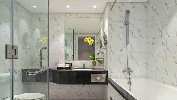 Ein modernes Badezimmer mit Duschkabine aus Glas, einer weißen Badewanne und einem Boden mit Marmorfliesen.