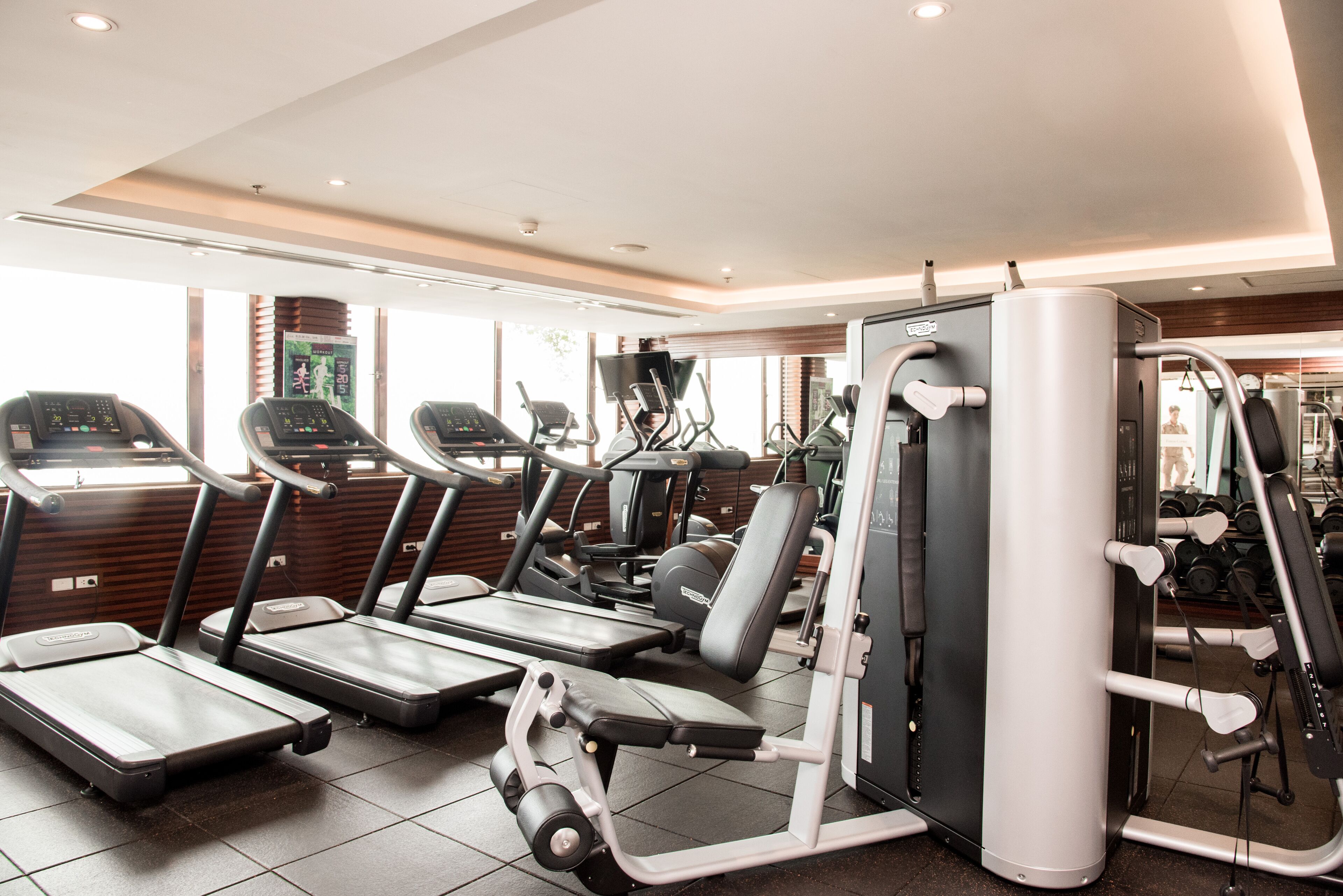 Een fitnessruimte met loopbanden, elliptische trainers en gewichttoestellen.