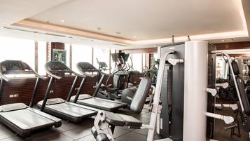 Een fitnessruimte met loopbanden, elliptische trainers en gewichttoestellen.