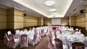 A banquet hall with round tables, white chairs, and pink sashes.
