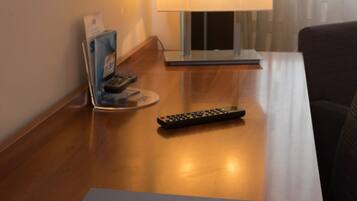A wooden table with a laptop, a remote control, and a lamp.