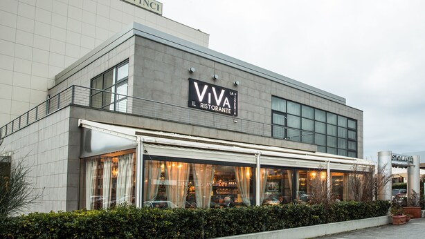 A modern building with a sign reading "HOTEL DAVINCI" and "VIVA IL RISTORANTE" indicating a restaurant.