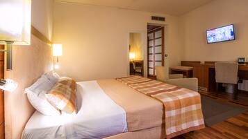 A hotel room with a bed, a desk, a chair, a television, and a bathroom.