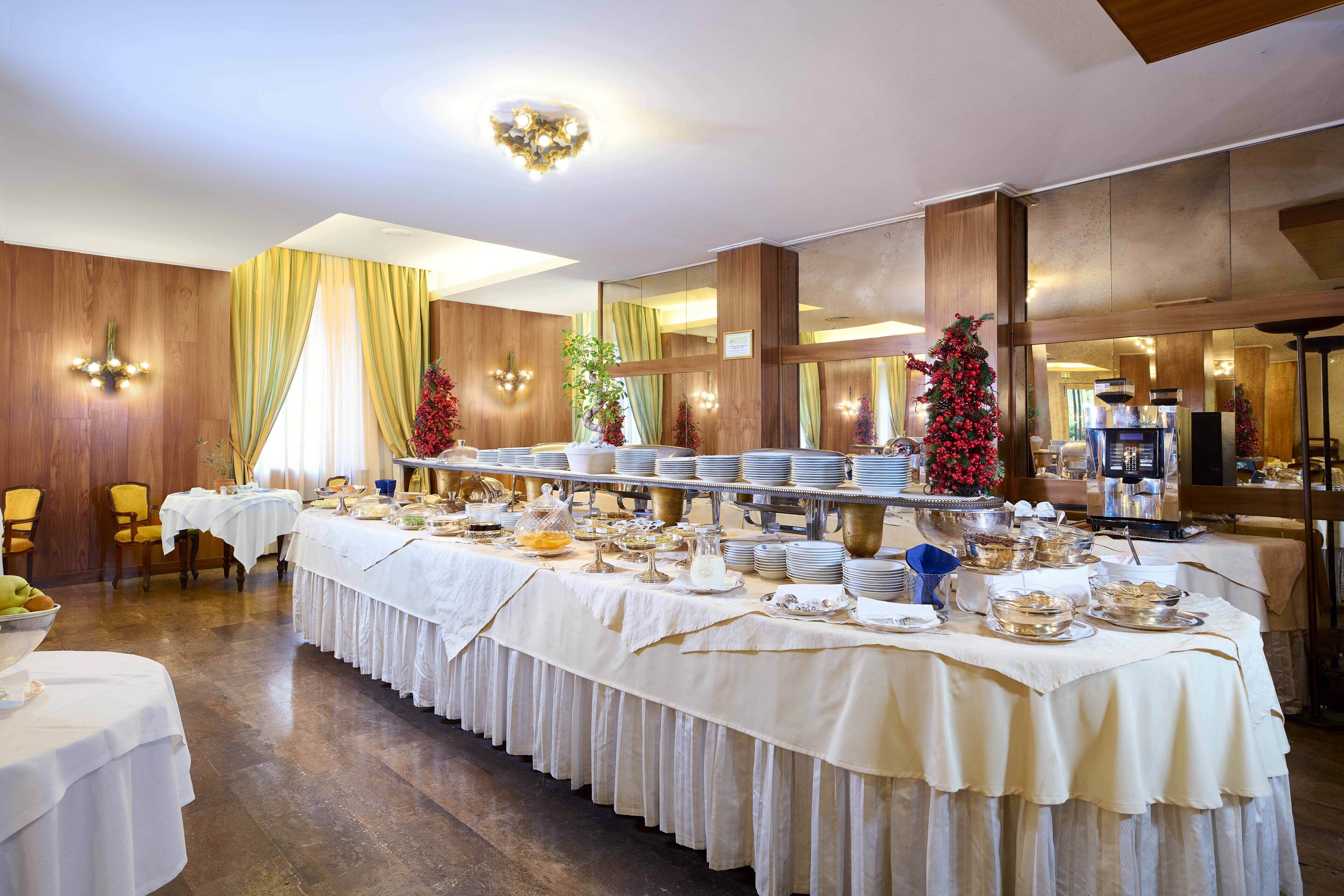 Montaje tipo bufé con varias estaciones de servicio, mesas cubiertas con manteles blancos y un árbol de Navidad al fondo.
