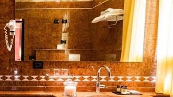 Un baño con lavamanos de mármol, un espejo, toallero y cortina de ducha.