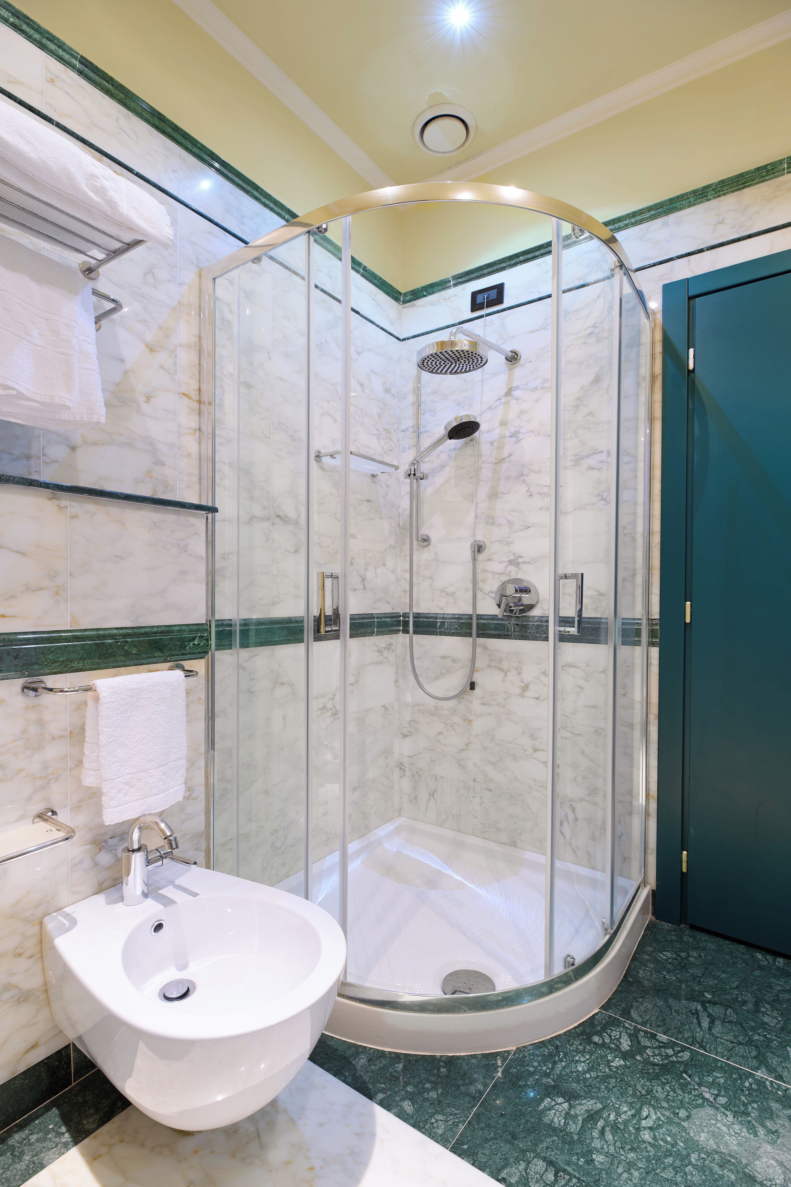 Un baño moderno con ducha de vidrio, lavamanos blanco y paredes de mármol.