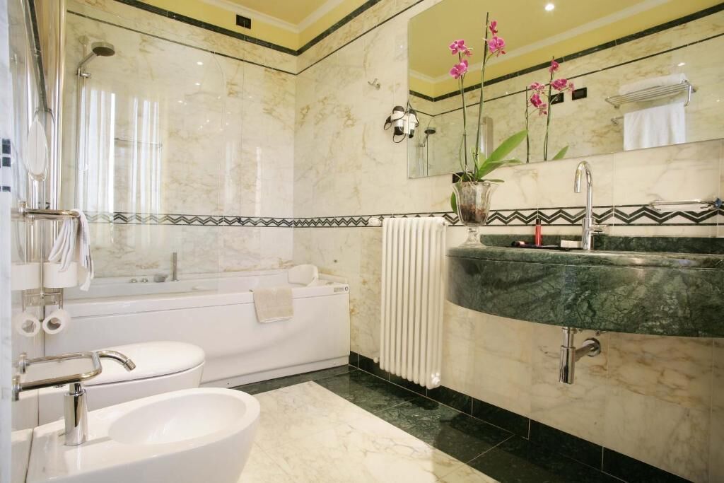 A bathroom with a bathtub, two sinks, a large mirror, and a potted orchid.