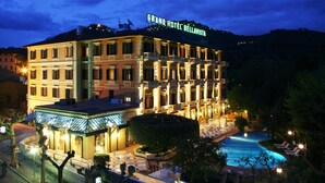 Un hôtel de luxe doté d’une piscine bien éclairée et d’un espace extérieur aménagé avec des sièges.