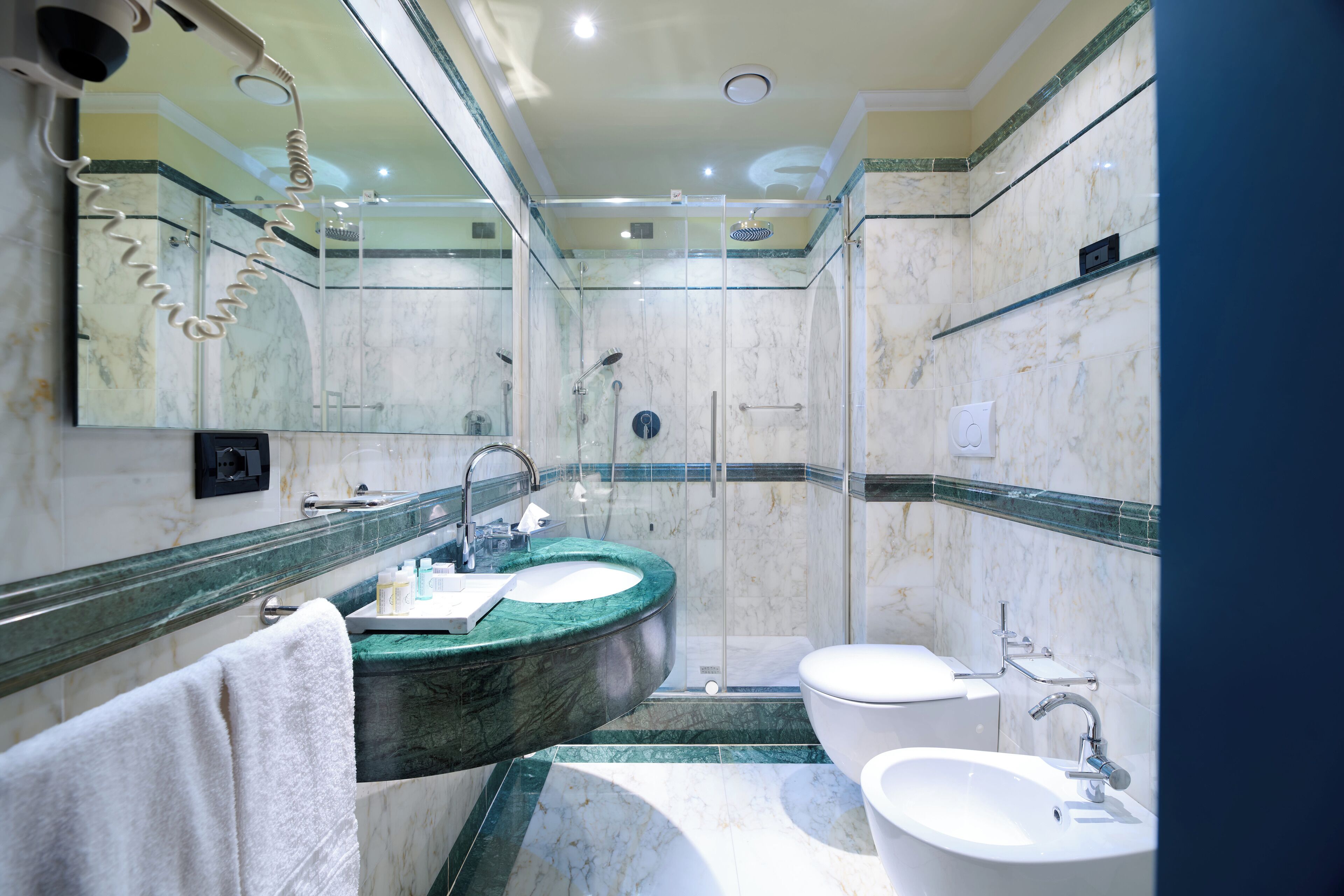 A bathroom with two sinks, a shower, and a toilet.