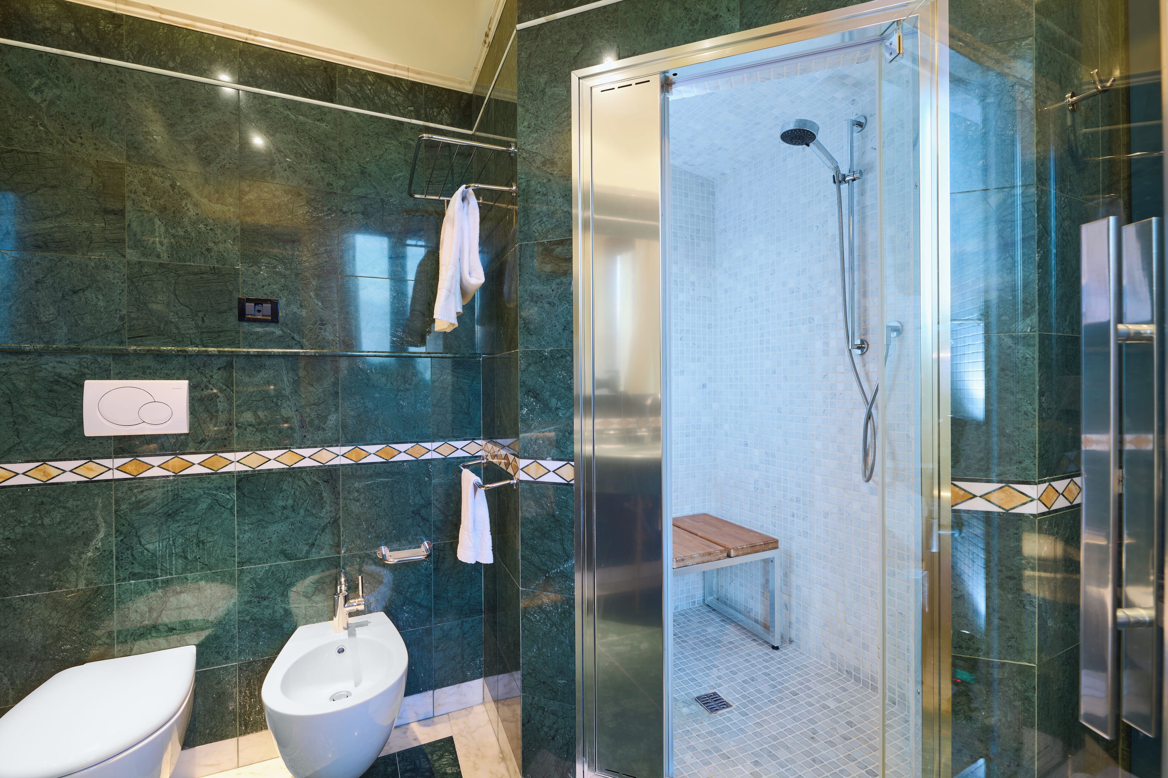 Un baño moderno con ducha envuelta en vidrio, un bidé y un inodoro.