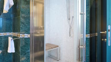 Eine begehbare Glasdusche mit Sitzbank, Marmorwänden und einem Handtuchhalter.