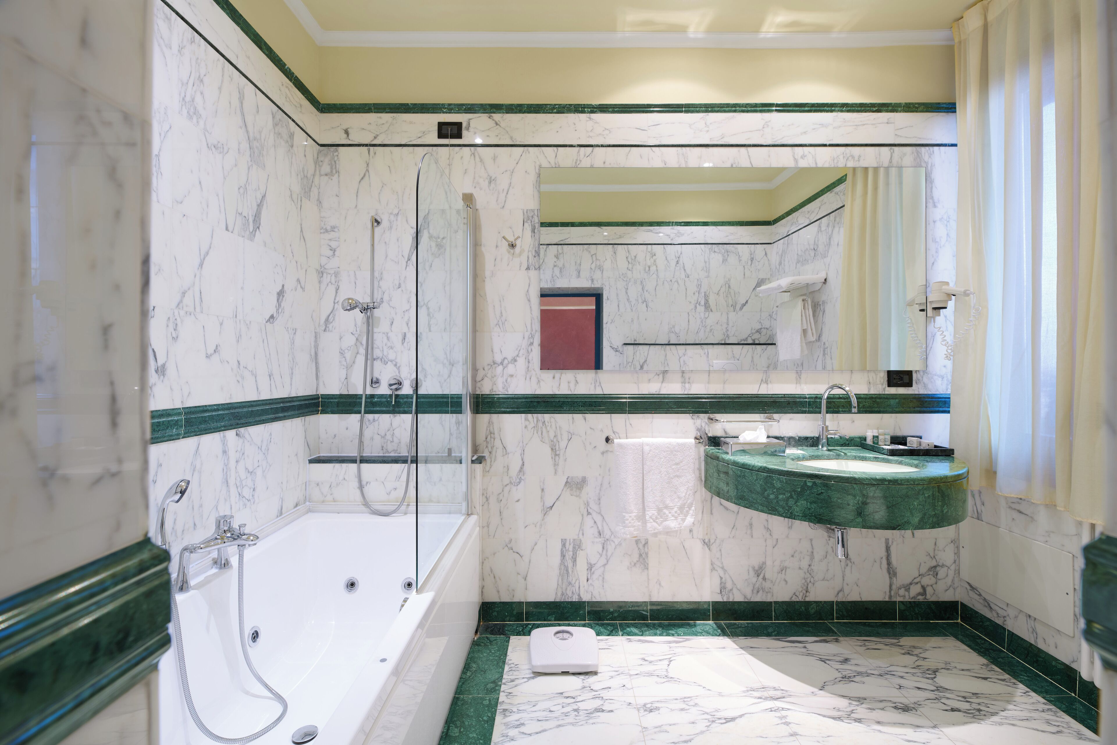 A bathroom with a marble floor, a bathtub, a shower, and a sink.