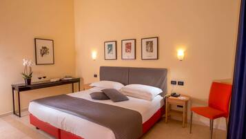 Quarto de hotel bem organizado, com cama, mesa de cabeceira, cadeira e obra de arte na parede.